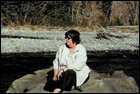 Patty Winter sitting on Sun Rock on the edge of Lynx River